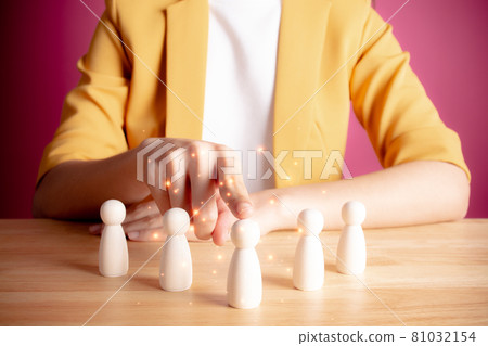 HR or human resource management concept. Young woman in yellow suite choice of an employee leader from the crowd. businesswoman holds an employee in her hand. Pink background. 81032154