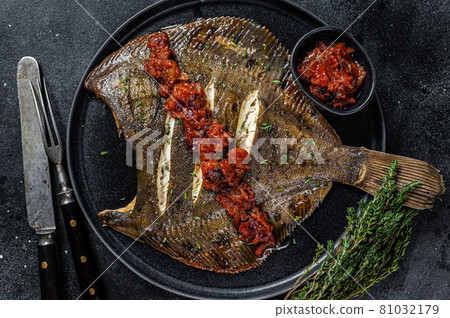 Roasted Flatfish or Flounder in a tomato sauce. Black background. Top view 81032179