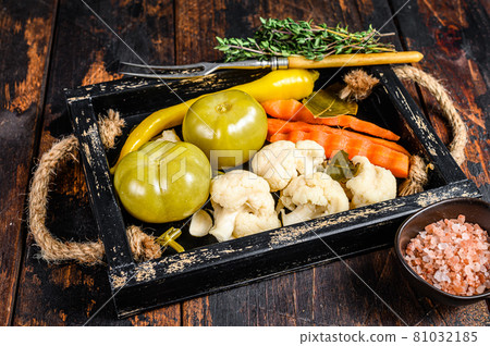 Homemade marinated and pickles vegetables preserve on a wooden tray. Dark wooden background. Top view 81032185