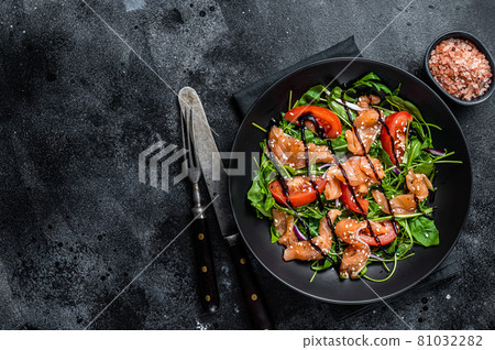 Salmon salad with fish slices, arugula, tomato and green vegetables. Black background. Top View. Copy space Salmon salad with fish slices, arugula, tomato and green vegetables. Black background. Top View. Copy space 81032282