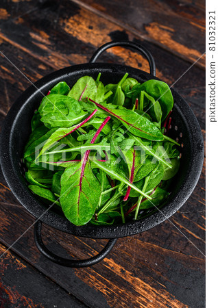Fresh raw mixed greens, spinach, swiss chard and arugula. Dark wooden background. Top view Fresh raw mixed greens, spinach, swiss chard and arugula. Dark wooden background. Top view 81032321