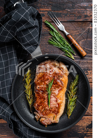 Grilled striploin beef meat steak in a pan with herbs. Dark wooden background. Top view Grilled striploin beef meat steak in a pan with herbs. Dark wooden background. Top view 81032370