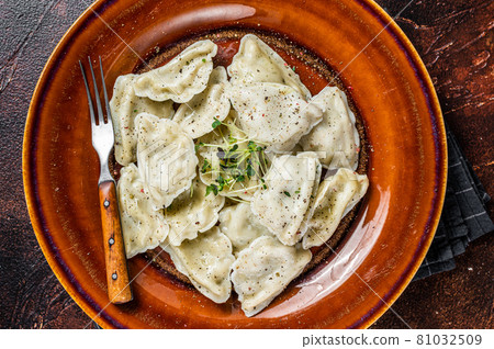 Polish Pierogi Dumplings with potato in a plate with herbs and butter. Dark background. Top View Polish Pierogi Dumplings with potato in a plate with herbs and butter. Dark background. Top View 81032509