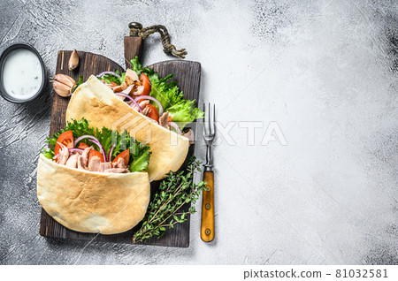 Pita sandwich with roasted chicken, vegetables and delicious sauce. White background. Top view. Copy space Pita sandwich with roasted chicken, vegetables and delicious sauce. White background. Top view. Copy space 81032581