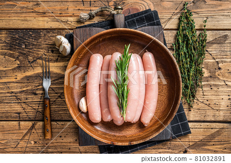 Poultry raw sausages in a wooden palte with herbs. wooden background. Top view Poultry raw sausages in a wooden palte with herbs. wooden background. Top view 81032891
