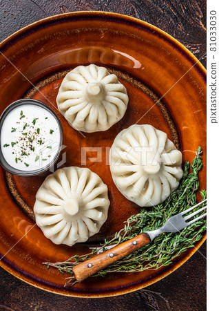 Khinkali Dumplings with beef and lamb meat on rustic plate with herbs. Dark background. Top view Khinkali Dumplings with beef and lamb meat on rustic plate with herbs. Dark background. Top view 81033030