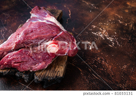 Raw lamb mutton thigh on butcher table. Dark background. Top view. Copy space 81033131