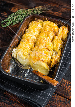 Potato casserole Gratin Dauphinois in a baking dish. Dark wooden background. Top View Potato casserole Gratin Dauphinois in a baking dish. Dark wooden background. Top View 81033154