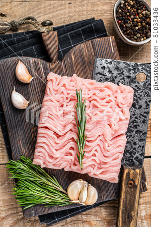 Raw minced chicken and turkey meat on wooden chopping board with butcher cleaver. wooden background. Top view Raw minced chicken and turkey meat on wooden chopping board with butcher cleaver. wooden background. Top view 81033436