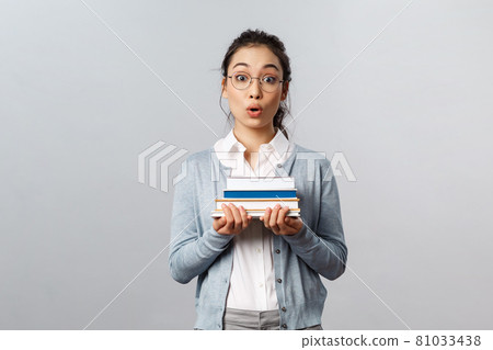 Education, teachers, university and schools concept. Surprised and amused smart nerdy asian female student, carry books for classes, look wondered and impressed camera, listen to interesting story 81033438