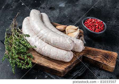 Raw Munich white sausage weisswurst on wooden board. Black background. Top view 81033507