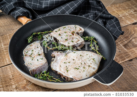 Fresh raw wolffish fillet steaks in a pan with herbs. wooden background. Top view Fresh raw wolffish fillet steaks in a pan with herbs. wooden background. Top view 81033530