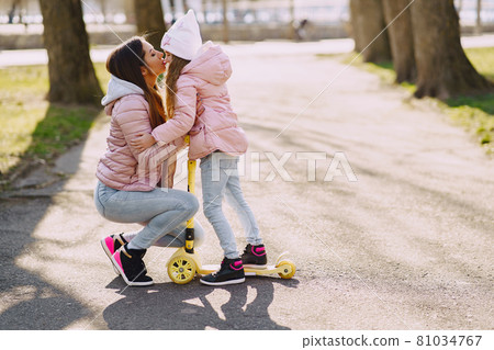 Mother with daughter in a spring park with skate 81034767