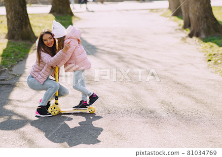 Mother with daughter in a spring park with skate 81034769