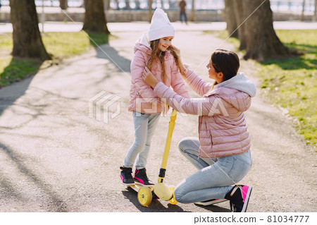 Mother with daughter in a spring park with skate 81034777