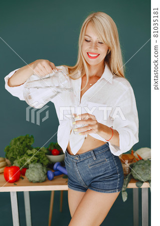 Beautiful and sporty girl in a kitchen with a vegetables Beautiful and sporty girl in a kitchen with a vegetables 81035181