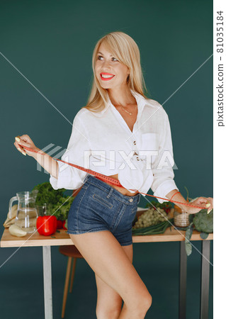 Beautiful and sporty girl in a kitchen with a vegetables Beautiful and sporty girl in a kitchen with a vegetables 81035184