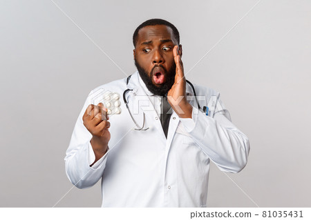 Flu, disease, healthcare and medicine concept. Worried and embarrassed african-american doctor mixed-up prescribtions, give wrong medication to patient, facepalm and look at drugs with concern 81035431
