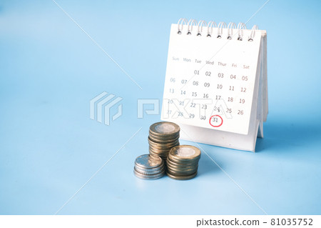 stack of coins and calendar on blue background 81035752