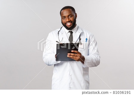 Medicine, covid19, treatment and hospital concept. Handsome african-american doctor treating patient, listening to person diseasy or symptoms, writing down clipboard during check-up Medicine, covid19, treatment and hospital concept. Handsome african-american doctor treating patient, listening to person diseasy or symptoms, writing down clipboard during check-up 81036191