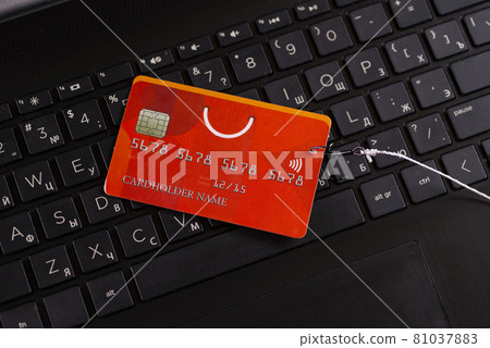 Internet fraud using computer technology, stealing money on the Internet, stealing credit card data. Hook hooked credit card on computer keyboard background 81037883