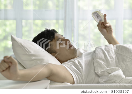 Portrait of happy Asian man waking up in bed in the morning 81038107