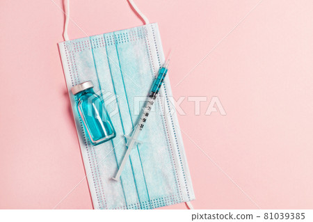 Vial vaccine, glass ampoules and a syringe with a medicine, medical protective mask on pink background. Gdobal vaccination, adults and children Vial vaccine, glass ampoules and a syringe with a medicine, medical protective mask on pink background. Gdobal vaccination, adults and children 81039385