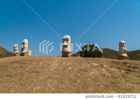 The Republic of Crimea. July 11, 2021. Stone heads sticking out of the ground near Mount Alchak in Sudak, which are like copies similar to statues from Easter Island. 81039722