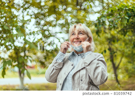 End of coronavirus epidemic. Happy Caucasian adult 50 years old taking off medical mask at summer park. Covid virus defeated. We won. End of coronavirus epidemic. Happy Caucasian adult 50 years old taking off medical mask at summer park. Covid virus defeated. We won. 81039742