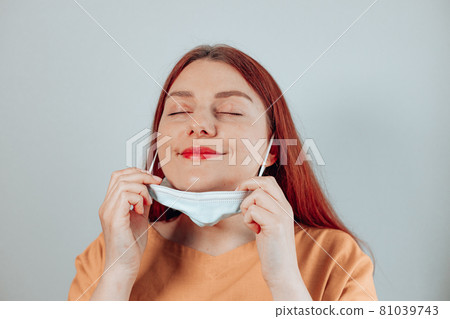 Caucasian woman taking off protective medical mask . We won. No more quarantine. 81039743