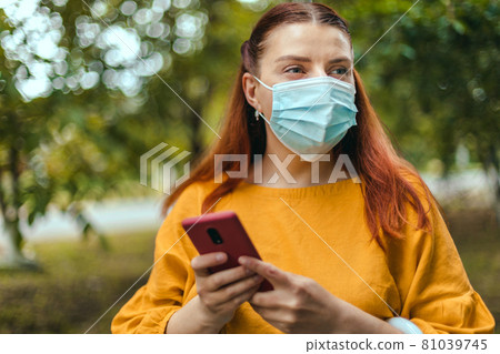 Happy Caucasian millennial woman wearing protective mask outdoor in city park during the Coronavirus Covid-19 pandemic Happy Caucasian millennial woman wearing protective mask outdoor in city park during the Coronavirus Covid-19 pandemic 81039745