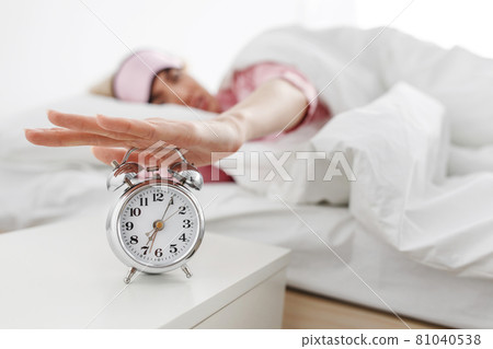 Alarm clock ringing, woman waking up in early morning for work, sleeping disorder Alarm clock ringing, woman waking up in early morning for work, sleeping disorder 81040538