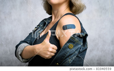 COVID-19 vaccinated young woman showing arm with plaster COVID-19 vaccinated young woman showing arm with plaster 81040559