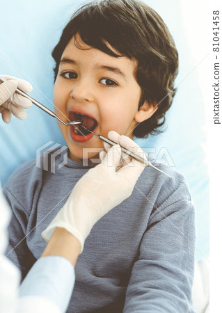 Little arab boy sitting at dental chair with open mouth during oral checking up with dentist doctor. Stomatology concept 81041458