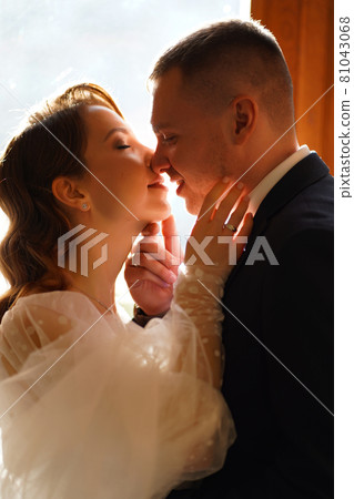 silhouettes of the bride and groom in sunlight through the glass in the door. 81043068
