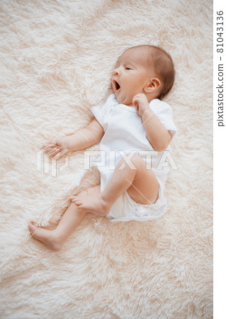 yawning newborn baby lying on a soft blanket. yawning newborn baby lying on a soft blanket. 81043136