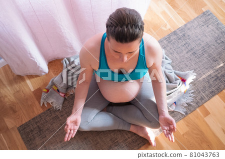 Pregnancy yoga meditation. Full length healthy pregnant woman doing yoga exercise at home. Pregnancy yoga meditation. Full length healthy pregnant woman doing yoga exercise at home. 81043763