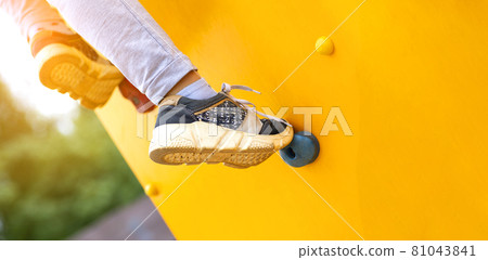 Close up image of a child's foot on a climbing wall 81043841