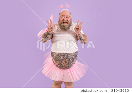 Excited man with overweight in fairy suit shows peace gestures on purple background Excited man with overweight in fairy suit shows peace gestures on purple background 81043910