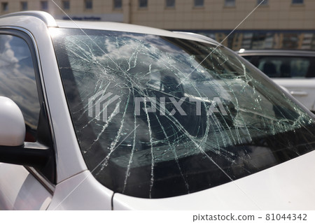 Closeup of cracks on broken car windshield 81044342
