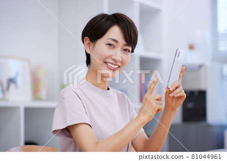 在客廳使用智能手機的中年婦女 在客廳使用智能手機的中年婦女 81044961