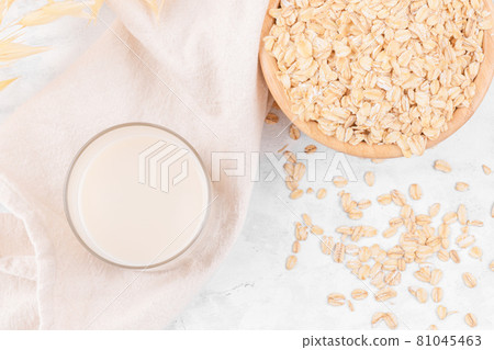 Glass with oat milk and a bowl with oat flake on white stone table, top view Glass with oat milk and a bowl with oat flake on white stone table, top view 81045463