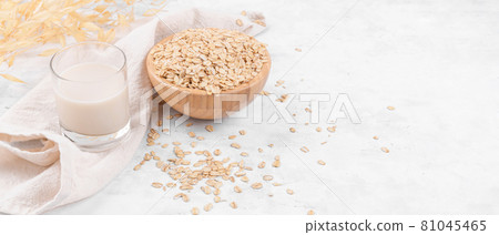 Glass with oat milk and a bowl with oat flake on white stone table Glass with oat milk and a bowl with oat flake on white stone table 81045465