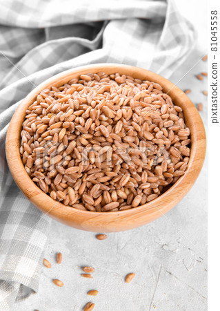 Wholegrain uncooked raw spelt farro in wooden bowl on grey stone table Wholegrain uncooked raw spelt farro in wooden bowl on grey stone table 81045558