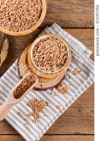 Wholegrain uncooked raw spelt farro in bowl on the wooden background 81045560