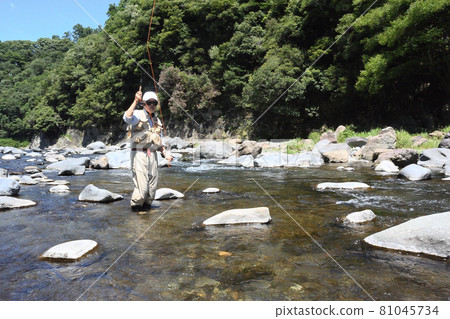 An angler who enjoys fly fishing in a wide and beautiful mountain stream An angler who enjoys fly fishing in a wide and beautiful mountain stream 81045734
