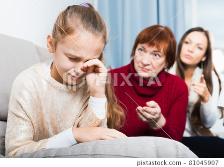 Little girl crying while mom and granny scolding her Little girl crying while mom and granny scolding her 81045907