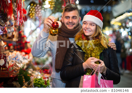 Joyful couple in Christmas hat with Christmas toys at fair 81046146