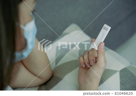 Asian woman using COVID-19 antigen test. 81046620