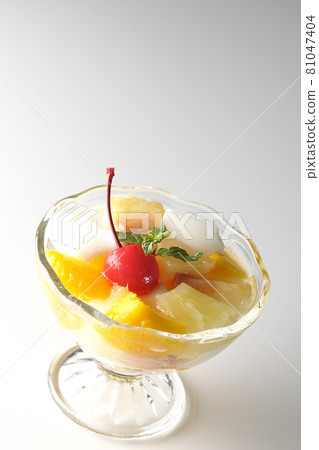 在白色背景上拍攝了含有牛奶罐、菠蘿、芒果、白桃、櫻桃和橙子等水果的水果潘趣酒。 81047404